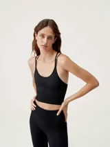 Top deportivo de sujeción media con diseño seamless, tirantes finos cruzados en la espalda y detalle de textura en el frente.