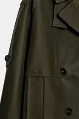 Trench corto Zara Woman Collection confeccionado en hilatura con algodón, en color verde militar. Presenta cuello solapa, manga larga con trabillas y botones en los puños, bolsillos delanteros, bajo asimétrico y cierre frontal cruzado con botones.