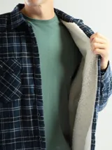 Sobrecamisa de franela a cuadros azul, verde y blanco, con forro de corderito blanco, cuello clásico, cierre frontal con botones, mangas largas y dos bolsillos con solapa abotonada en el pecho.