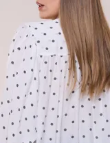 Blusa holgada de gasa texturizada color blanco con estampado de lunares negros, escote en V con botones frontales, mangas 3/4 abullonadas y puños elásticos.