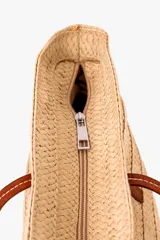 Bolso tipo capazo color beige con diseño trenzado y asas largas de cuero sintético marrón.