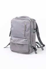 Mochila de viaje color gris, con diseño funcional que incluye múltiples compartimentos con cierre, bolsillo frontal vertical y correas ajustables con hebillas.