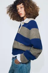 Jersey de punto a rayas horizontales azules y grises, con cuello tipo polo en color beige y cierre frontal con botones.