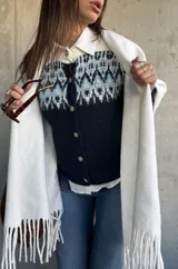 Cardigan de punto en color azul marino con diseño jacquard en tonos celestes y blancos en la parte superior. Presenta cuello redondo, cierre frontal con botones y mangas largas.