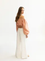 Blusa corta de lino color salmón, con escote elástico estilo campesino y mangas largas abullonadas con puños elásticos.