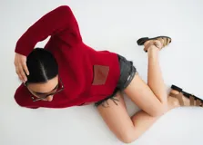 Campera tejida con textura vanizada a rayas horizontales en blanco y negro, con cierre frontal y flecos negros en forma de V en el pecho.