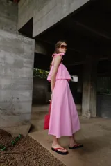 Vestido midi de color rosado con escote recto elástico y tirantes anchos con lazos ajustables. Presenta cintura elástica y bolsillos laterales ocultos en la costura.