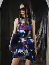 Falda corta asimétrica con diseño envolvente y estampado digital en tonos violeta, azul, negro, blanco y gris.