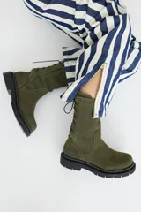 Botas de caña media color verde militar, con acordonado trasero de gamuza y suela track color negro.