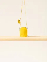 Bandolera amarilla con correa fina regulable y monedero colgante.