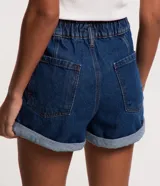 Short de jeans azul oscuro, corte holgado, cintura alta con elástico y trabillas, cierre con botón y cremallera, bolsillos y ruedo doblado.