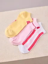 Pack de tres pares de medias de tobillo: un par amarillo con logo de flor rosa, un par rosa con dos rayas rojas en el borde y un par blanco con rayas rojas y rosas.