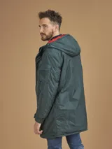 Campera de abrigo azul marino con capucha, cierre frontal con botones y cremallera, múltiples bolsillos y forro interior naranja.