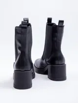 Bota tipo chelsea de caña alta confeccionada en cuero sintético, con paneles elásticos laterales, plataforma dentada y taco cuadrado.