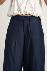 Pantalón wide leg de tiro medio y corte holgado, color azul marino, con pinzas en la parte frontal, bolsillos laterales y cierre con botón.