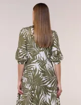 Vestido midi de silueta holgada en color blanco con estampado de hojas verdes. Presenta escote en V con cuello mao y botones frontales en la pechera, mangas tres cuartos abullonadas con puños elásticos y falda de corte evasé con niveles fruncidos.