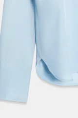 Camisa de cuello solapa y escote en pico, con manga larga y cierre frontal mediante botones. Presenta un diseño fluido con bajo asimétrico y aberturas laterales.