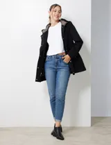 Gabardina impermeable negra, con capucha desmontable, cierre central oculto con botones a presión, bolsillos delanteros y cintura ajustable con jareta interna. Incluye forro interno desmontable.