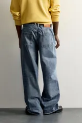 Jeans baggy fit de tiro medio, confeccionados en denim de algodón con efecto lavado. Presentan un diseño de cinco bolsillos, corte holgado y amplio en toda la pierna, con cierre frontal de botones.