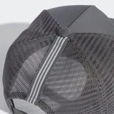 Gorra tipo trucker de cinco paneles en color gris, con paneles traseros y laterales de malla transpirable. Presenta el logo del Trifolio de Adidas bordado en blanco en la parte frontal, visera precurvada y cierre trasero ajustable a presión.