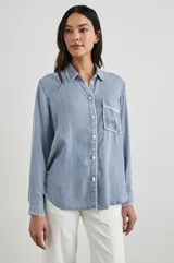 Camisa celeste de denim tencel, de corte holgado, con cuello clásico, cierre frontal con botones y bolsillo en el pecho con detalle bordado.