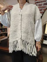 Ruana de lana color crudo, tejida a mano con diseño calado y flecos largos en el ruedo.