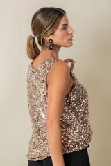 Blusa sin mangas confeccionada en tela cubierta de lentejuelas doradas y plateadas, con escote redondo y corte holgado.