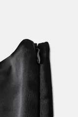 Falda pantalón negra de tiro alto, confeccionada en tejido satinado con un borde inferior de encaje negro festoneado. Incluye forro interior y cierre lateral oculto.