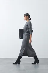 Vestido midi de punto en color gris, con diseño de tejido acanalado vertical, cuello redondo y mangas largas. Presenta una silueta recta y fluida.