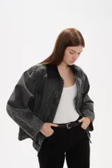 Campera de jean con lavado gris desgastado, cuello camisero en pana negra, cierre frontal con botones y bolsillos laterales amplios.