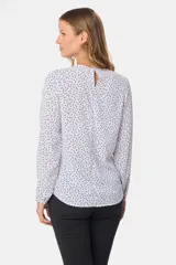 Blusa blanca con estampado de lunares negros, de manga larga y cuello redondo con abertura en la espalda.