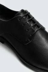 Zapato de vestir tipo derby, color negro, fabricado en piel con horma cuadrada y suela con ligero tacón.