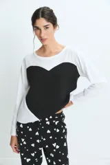 Pijama compuesto por una remera de manga larga blanca y un pantalón negro con estampado de corazones blancos. El pantalón cuenta con cintura elástica para mayor comodidad.