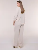 Chaqueta liviana color beige de silueta fluida y diseño abierto, con solapa caída, cintura con cordón ajustable y mangas 3/4 con presilla y argolla metálica.