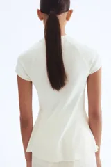 Top de punto fino color blanco, con cuello redondo acanalado, mangas cortas raglán y silueta acampanada tipo peplum en el bajo.