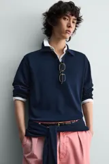 Jersey de punto color azul marino, de corte relajado, con cuello solapa y cierre frontal de tres botones. Presenta mangas largas y acabados en rib en puños y bajo.