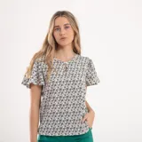 Blusa blanca con estampado de flores azules y verdes, cuello redondo con abertura en forma de gota y mangas cortas amplias.