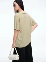 Remera de corte holgado y silueta cómoda, con escote en V y mangas cortas. Presenta costuras visibles en el cuello y los hombros, con un diseño minimalista y versátil.