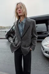 Blazer de corte sastrero confeccionado en tejido de lana con diseño de espiga. Presenta cuello con solapas, hombreras, cierre frontal con un botón y bolsillos delanteros con solapa.