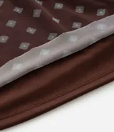 Blusa tipo bata confeccionada en tule con forro interior, escote en V, mangas cortas con detalle de lazo y cintura fruncida. Presenta un estampado geométrico tipo pañuelo.