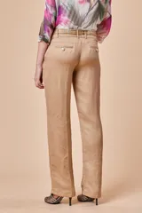 Pantalón de vestir color beige, de lino y seda, con textura firme, pretina ancha con dos botones plateados, cinto de cordón con strass y bolsillos laterales.