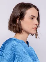 Blusa naranja de manga corta con escote en V y textura plisada.