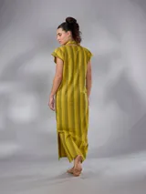 Vestido largo de lino y algodón con diseño de rayas verticales en tonos mostaza y verde. Presenta escote en V, cuello solapa ancho, mangas cortas con diseño capa, corte recto y lazo ajustable en la cintura.