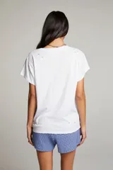 Remera blanca de algodón y poliéster con cuello redondo y mangas cortas. Estampado vintage del logo de la banda Guns N' Roses en el frente. Diseño con roturas y aspecto desgastado.