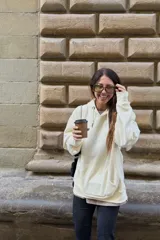 Buzo con capucha color crudo, de corte holgado y manga larga, con bolsillo canguro frontal.