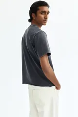 Remera de algodón con efecto lavado, color gris oscuro, corte regular fit, mangas cortas, hombros caídos, cuello redondo acanalado y bajo sin rematar.
