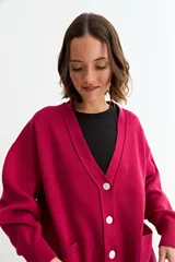 Cardigan de punto color fucsia, con cuello en V, cierre frontal con botones y bolsillos laterales. Presenta un diseño holgado con mangas largas y puños acanalados.