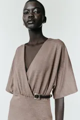 Vestido midi de escote en pico cruzado y manga corta. Presenta detalle de frunces en la cintura y un cinturón integrado con hebilla metálica a contraste.