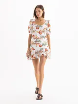 Minifalda blanca con estampado colorido y volados en la cadera, confeccionada en tejido elástico.