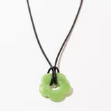 Collar con dije de flor verde y cordón negro.